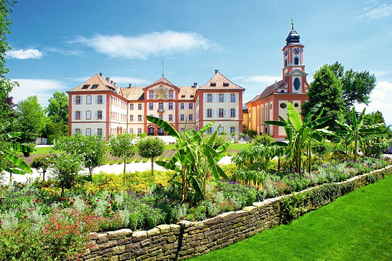 Ferienhotel am Bodensee mit blühendem Garten im Vordergrund