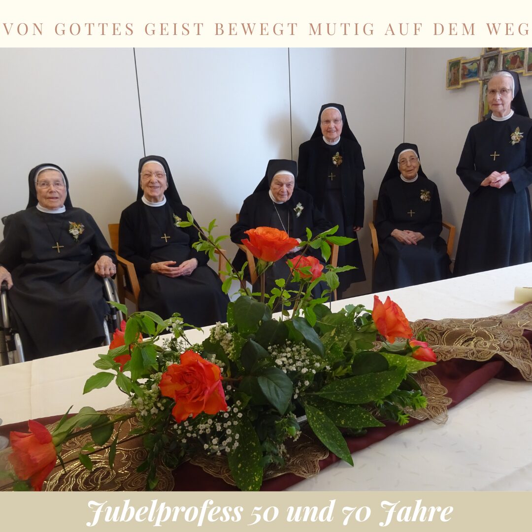 sechs Frauen sitzen an einem langen Tisch, der mit Blumen geschmückt ist.