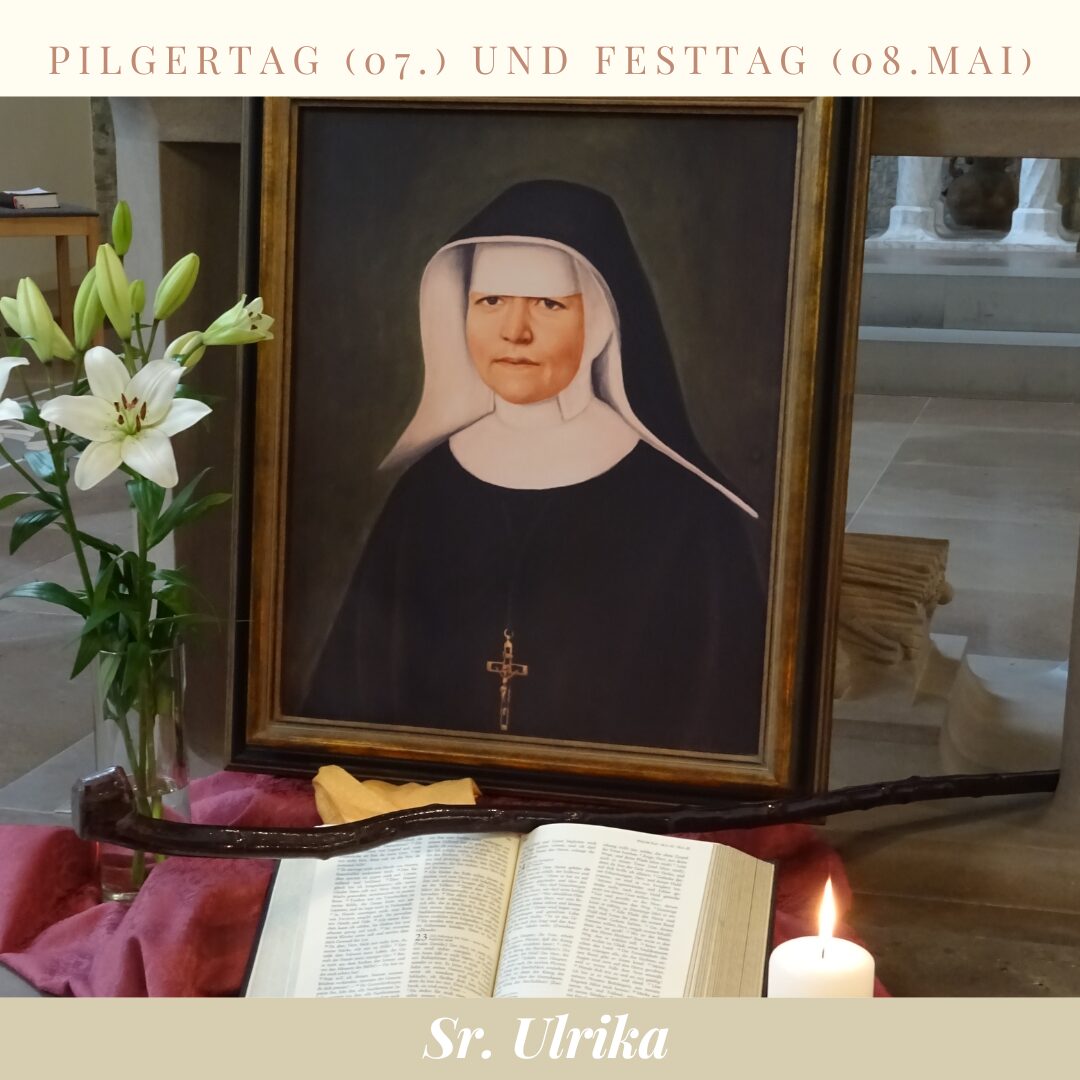 ein eingerahmtes Bild von der seligen Schwester Ulrika Nisch mit Blumen, einer Kerze und einer aufgeschlagenen Bibel davor