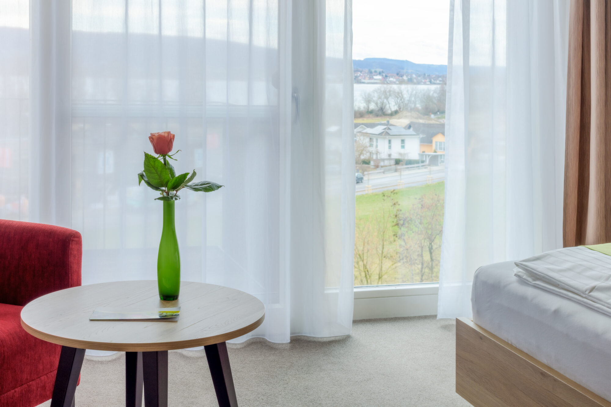 eine Rose auf einem kleinen Tisch neben einem Bett im Hotelzimmer